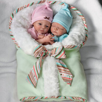 A baby doll in a basket with two babies.