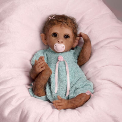 A baby monkey doll in a blue outfit.