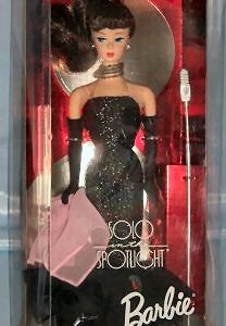 A barbie doll in black dress and gloves.