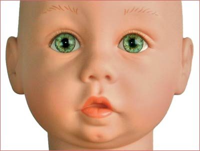 A doll head with green eyes and orange lips.