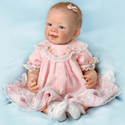 A baby doll wearing pink dress and shoes.