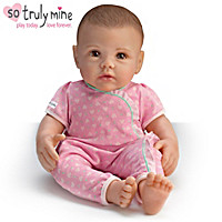 A baby doll wearing pink pajamas and sitting on the floor.