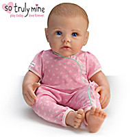 A baby doll wearing pink pajamas and sitting on the floor.