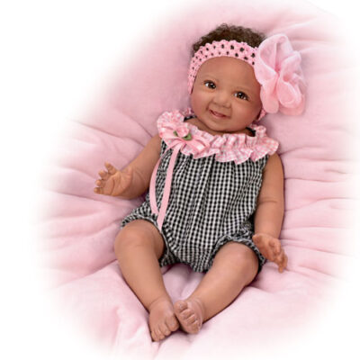 A baby doll is sitting on the bed