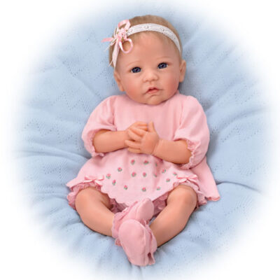 A baby doll is sitting on the bed with white background