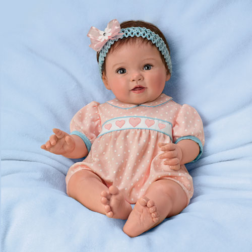 A baby doll is laying on the bed