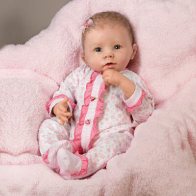 A baby girl sitting in a pink blanket.