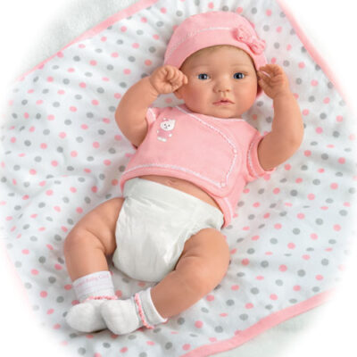 A baby doll laying on top of a blanket.