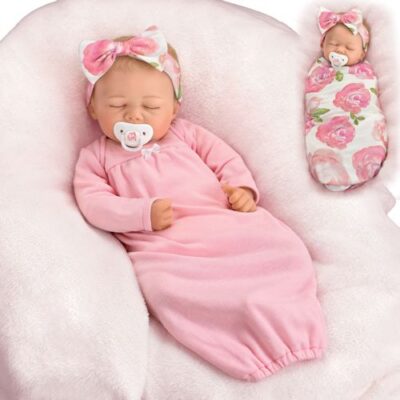 A baby doll is laying in a pink blanket