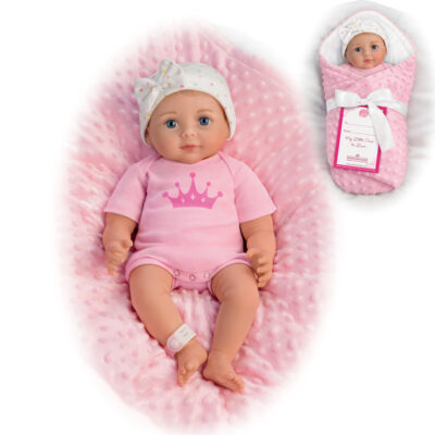 A baby doll is laying in a pink blanket.