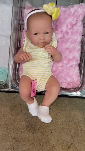A baby doll is sitting in a box